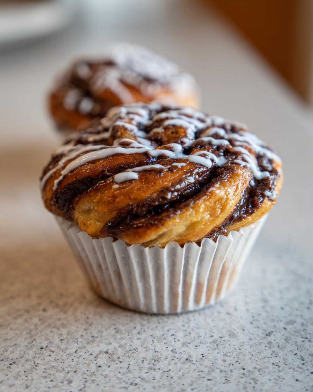 Close-up of a freshly baked Chocolate Hazelnut Babka Bun drizzled with white icing.