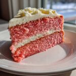 A close-up slice of moist Cortadillo Mexican Pink Cake with white frosting layers.