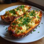 Two halves of baked sweet potato stuffed with creamy Butterkase cheese mixture and topped with fresh chives.