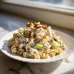 A close-up of Crunchy Pasta Tuna Salad with Yogurt Dressing, featuring pasta, tuna, celery, cranberries, and walnuts.