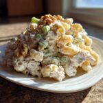 A mound of Crunchy Pasta Tuna Salad with Yogurt Dressing, featuring elbow macaroni, creamy sauce, celery, and walnuts, served on a white plate.
