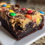 A close-up of a rich, fudgy Easter Egg Brownies with Peanut Butter layer, topped with colorful candy eggs.