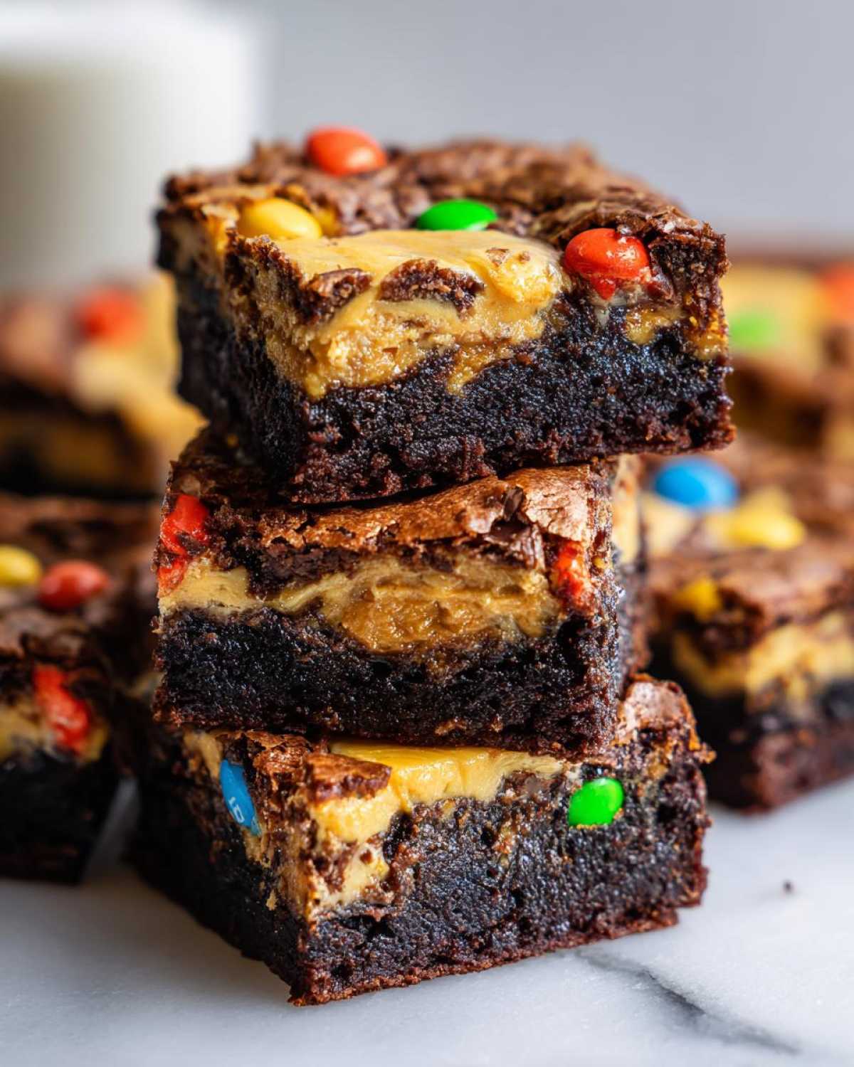 A stack of three rich, dark chocolate Easter Egg Brownies with Peanut Butter swirl and colorful candy pieces visible.
