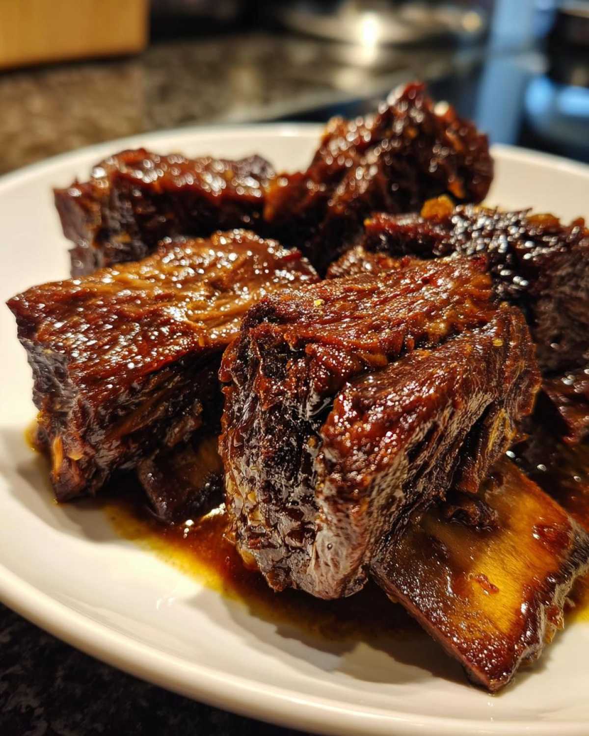 Close-up of tender, dark, glazed Filipino Beef Short Ribs Adobo pieces served on a white plate.