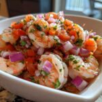 Close-up of vibrant Fresh Shrimp Ceviche with Citrus, featuring plump shrimp, diced red onion, and tomato in a white serving bowl.