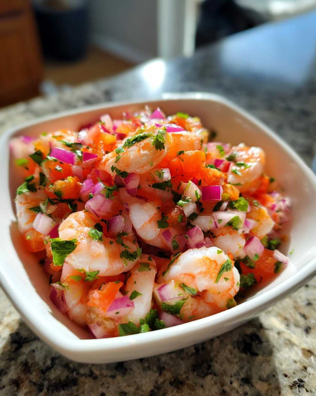 Close-up of vibrant Fresh Shrimp Ceviche with Citrus, mixed with diced red onion, tomato, and cilantro in a white bowl.