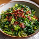 Close-up of a bowl filled with vibrant green Fried Cabbage with Crispy Bacon topping.