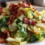 A close-up photo of tender, sautéed Fried Cabbage with Crispy Bacon pieces scattered on top.