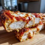Close-up of a thick slice of High-Protein Chicken Parm Pizza showing the juicy white chicken breast base under melted mozzarella and marinara sauce.