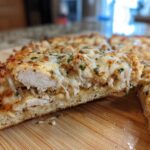 Cross-section view of a slice of High-Protein Chicken Parm Pizza showing thick layers of white chicken breast and melted mozzarella cheese.