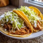 Two delicious Instant Pot Chicken Tacos filled with shredded chicken and topped generously with shredded cabbage.