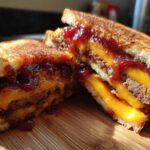 Close-up of a Leftover Meatloaf Sandwich cut in half, showing melted cheddar cheese, meatloaf, and spicy glaze on toasted bread.