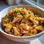 Close-up of a white bowl filled with savory Leftover Rotisserie Chicken Fried Rice, topped with green onions.