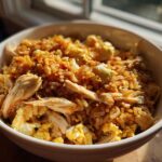 A close-up of a white bowl filled with savory Leftover Rotisserie Chicken Fried Rice and scrambled egg pieces.