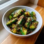 Close-up of smashed cucumbers tossed in a dark, spicy dressing, ready to serve as Logan Moffit's Din Tai Fung Cucumber Salad.