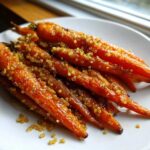 Close-up of glazed Miso Maple Carrots with Crunchy Quinoa piled on a white plate.