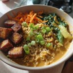 A close-up of Miso Peanut Ramen Bowls with Tofu, featuring crispy tofu cubes, noodles in miso broth, carrots, and green onions.