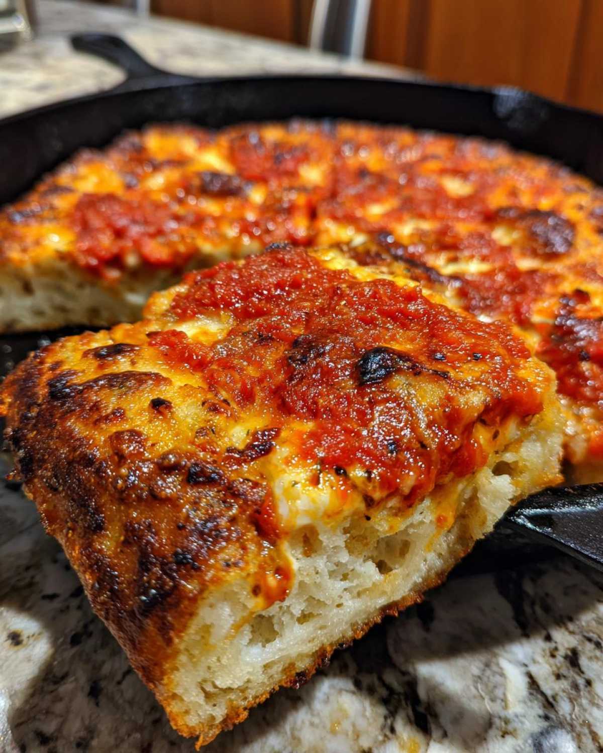 Close-up of a thick slice of No-Knead Simple Crispy Pan Pizza showing the airy crust and rich tomato topping.