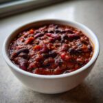 Close-up of a white bowl filled with rich, thick Pantry Staple Chili with Beans, featuring kidney and black beans.
