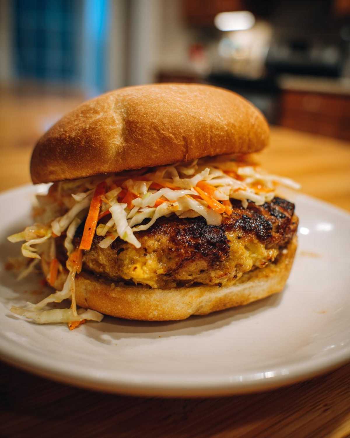 A close-up of a Roasted Cabbage Burger on a bun, topped generously with spicy slaw.