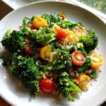 Close-up of a vibrant Sheet Pan Salad with Toasted Veggies featuring bright green broccoli florets, red and yellow cherry tomatoes, and fluffy quinoa.