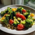 A plate featuring a vibrant Sheet Pan Salad with Toasted Veggies, including bright green broccoli florets, red cherry tomatoes, and yellow squash mixed with quinoa.