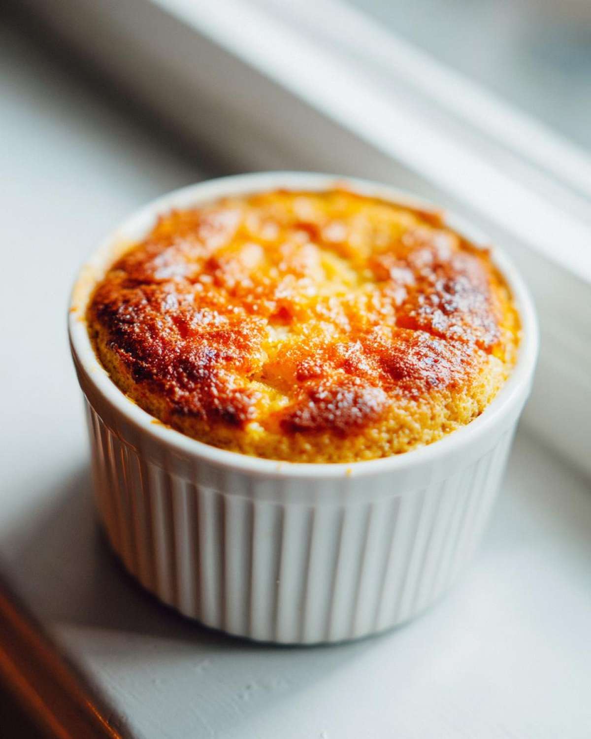 Close-up of freshly baked Single-Serving Carrot Cake Baked Oats with a golden-brown top in a white fluted ramekin.