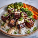 A close-up of Teriyaki Tofu Bowls featuring glazed tofu cubes over rice, drizzled with Kimchi Mayo and topped with sesame seeds and green onions.