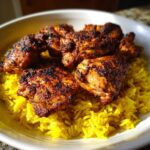 Close-up of seasoned, charred Trader Joe’s Chicken Shawarma pieces resting on bright yellow lemon rice in a white bowl.