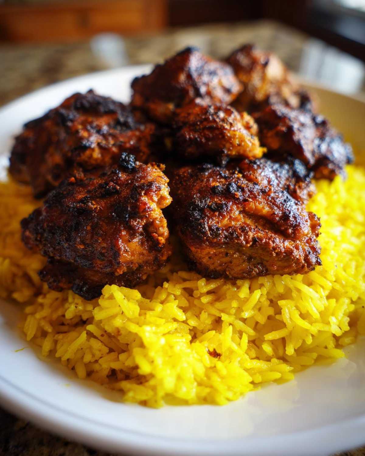 Close-up of seasoned Trader Joe’s Chicken Shawarma pieces served over vibrant yellow lemon rice on a white plate.