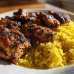 Close-up of grilled Trader Joe’s Chicken Shawarma pieces served over vibrant yellow lemon rice on a white plate.